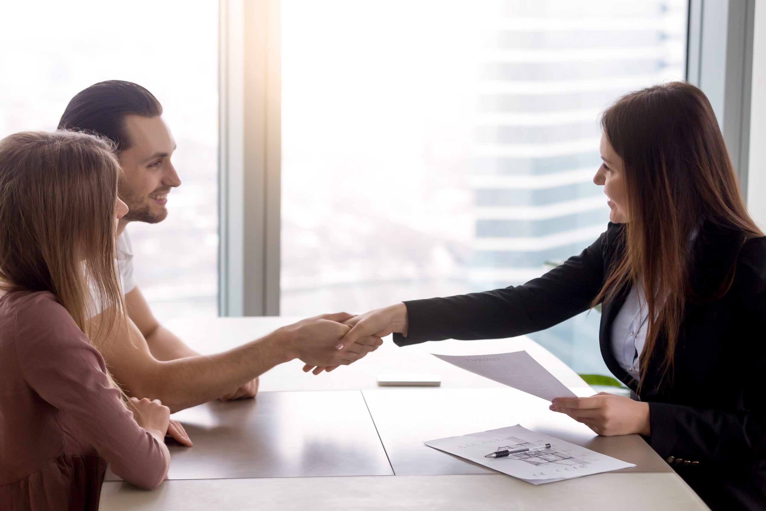 Young Smiling Couple Visiting Real Estate Agency Shaking Hands